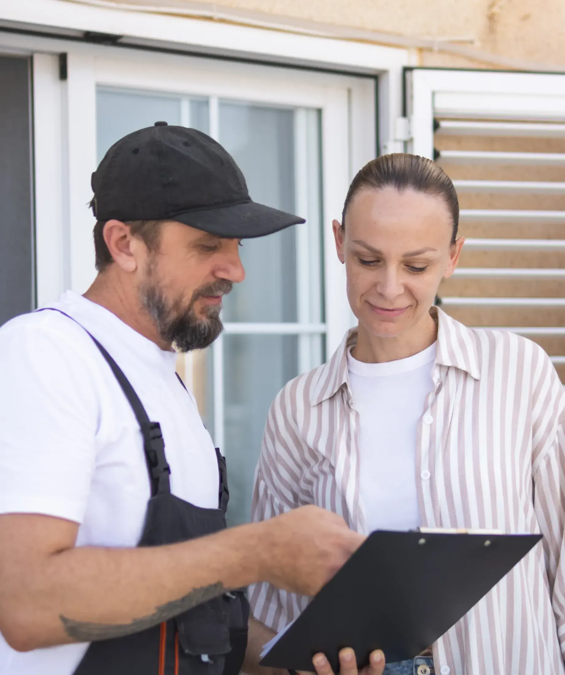 Homeowner and contractor reviewing paperwork on a clipboard together